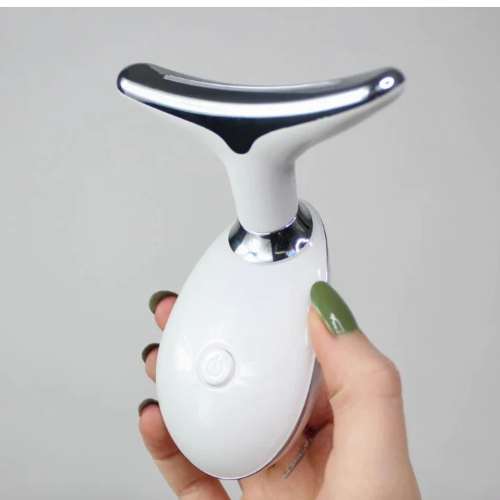 portable face massager being held in woman's hand.