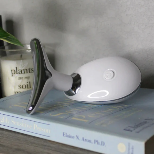 white pure aura face massager on a book.