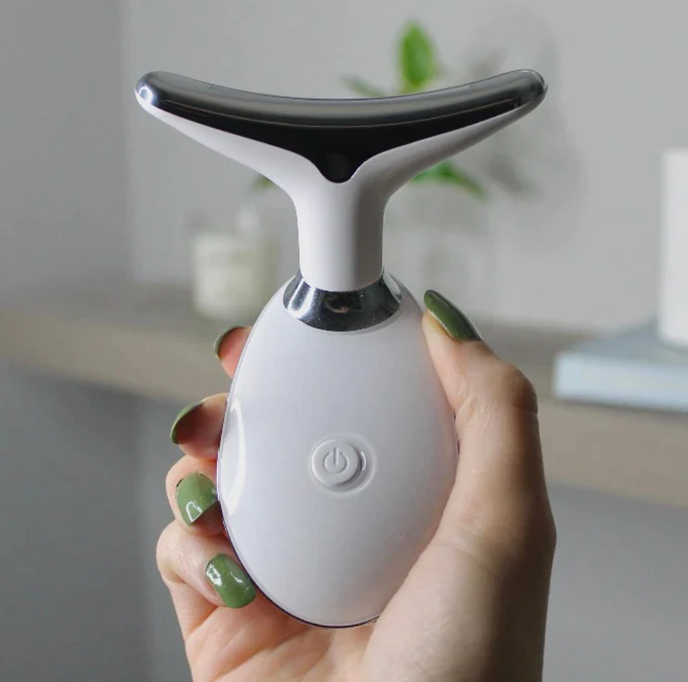 woman's hand holding a white pure aura face massager.